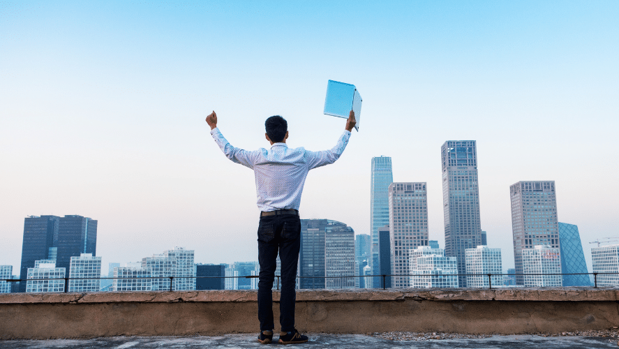 a man holding a laptop in front of buildings