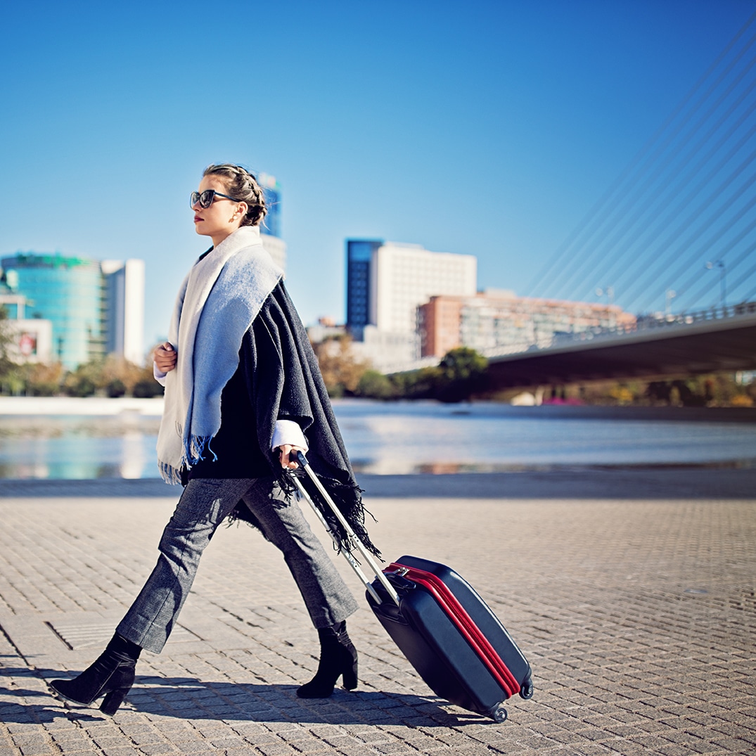 a woman walking down the street with a suitcase