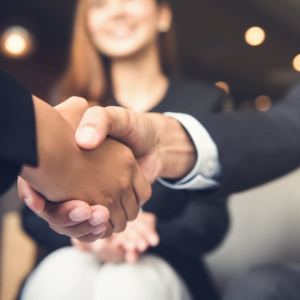 people shaking hands in front of a woman