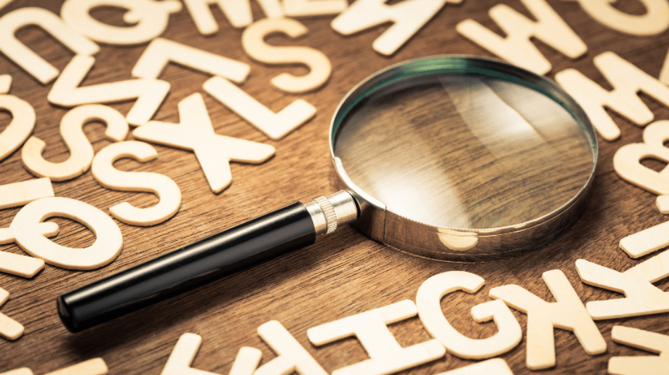 a magnifying glass on a table with various cutouts of letters