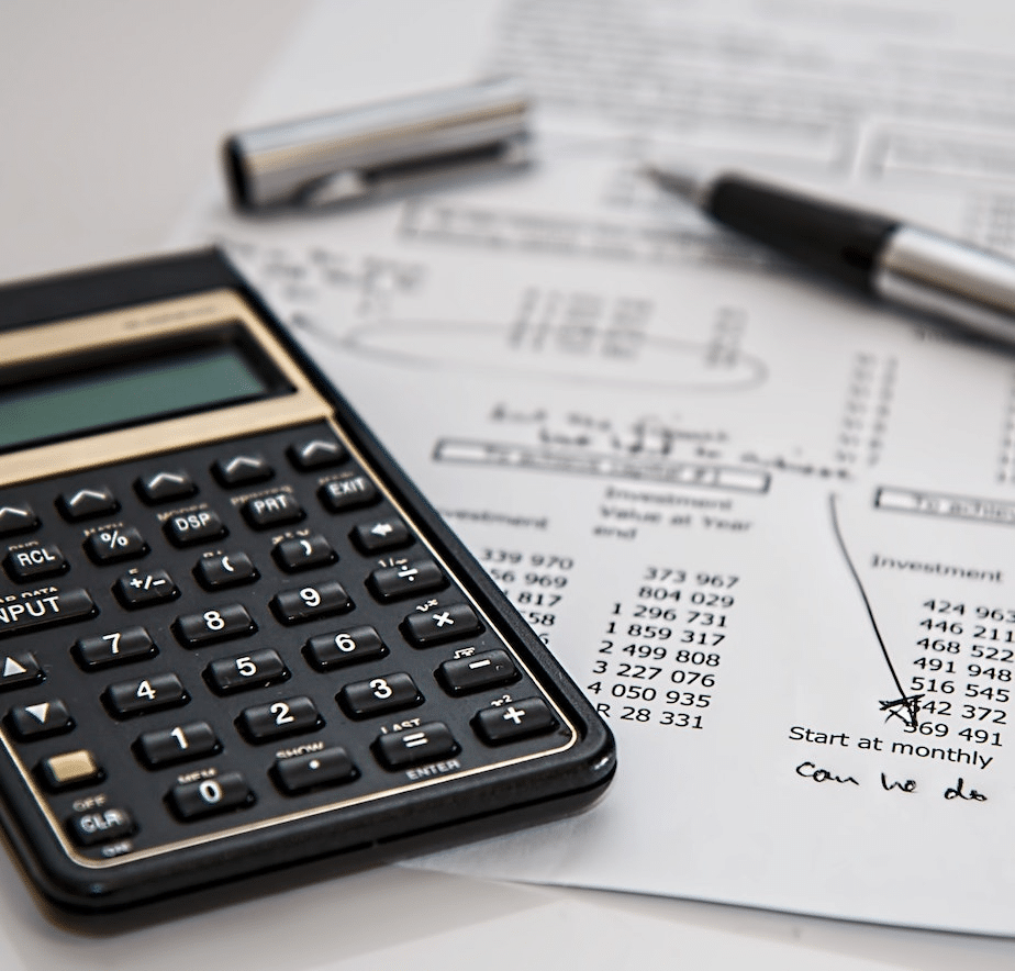 a table with a sheet of paper, calculator, and pen