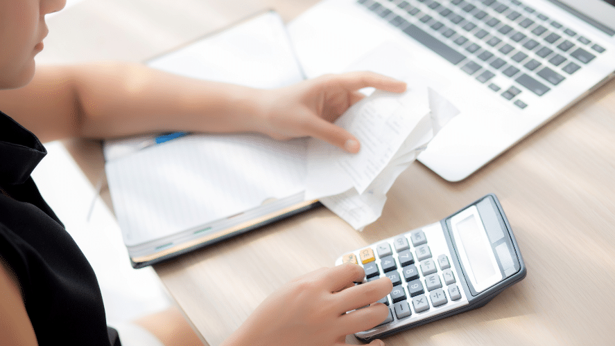 a person holding receipts and using a calculator