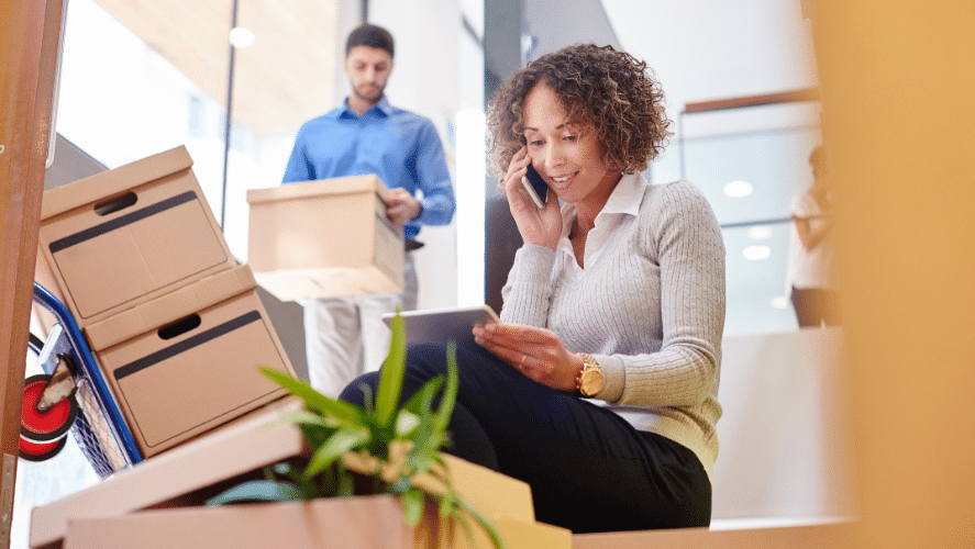 a woman on the phone in front of a man carrying boxes