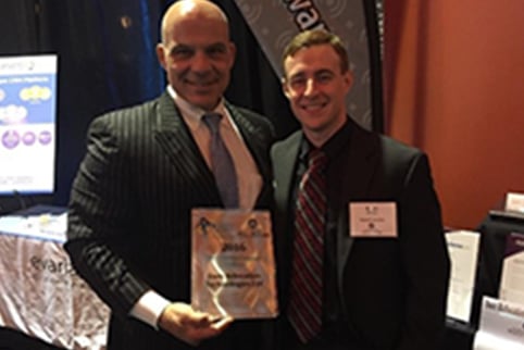 two men in suits holding an award plaque