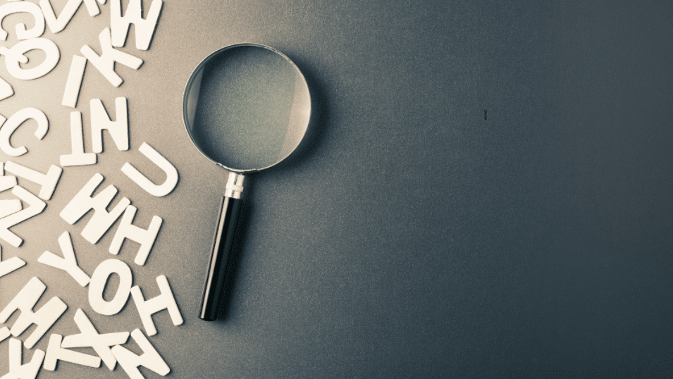 a table with a magnifying glass and paper letter cutouts