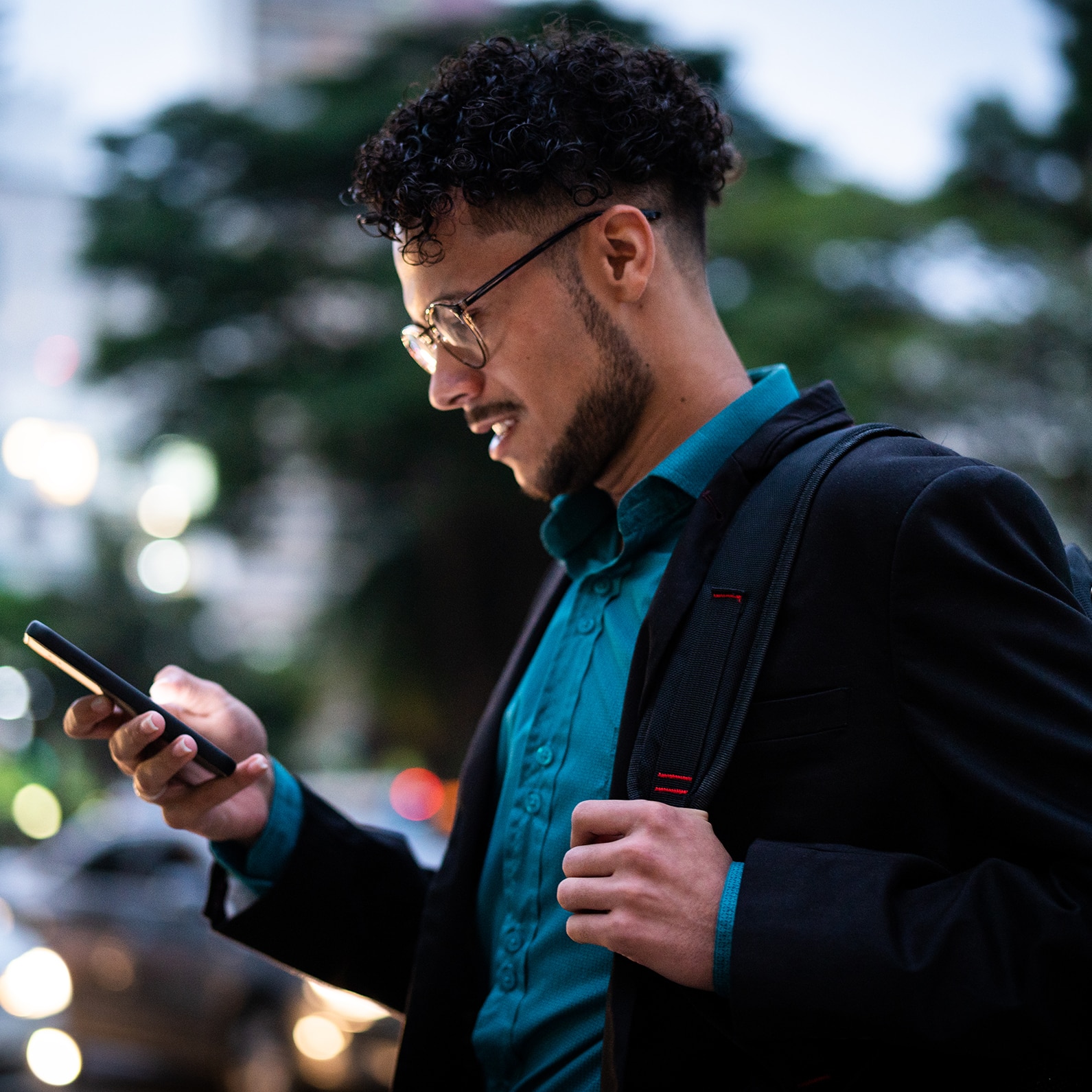 a man in a blue shirt and a black jacket is using a cell phone