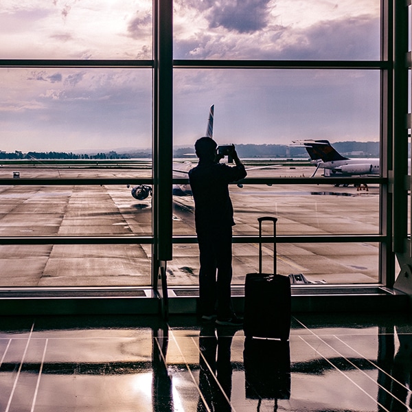 a man looking through an airport window towards the tarmac