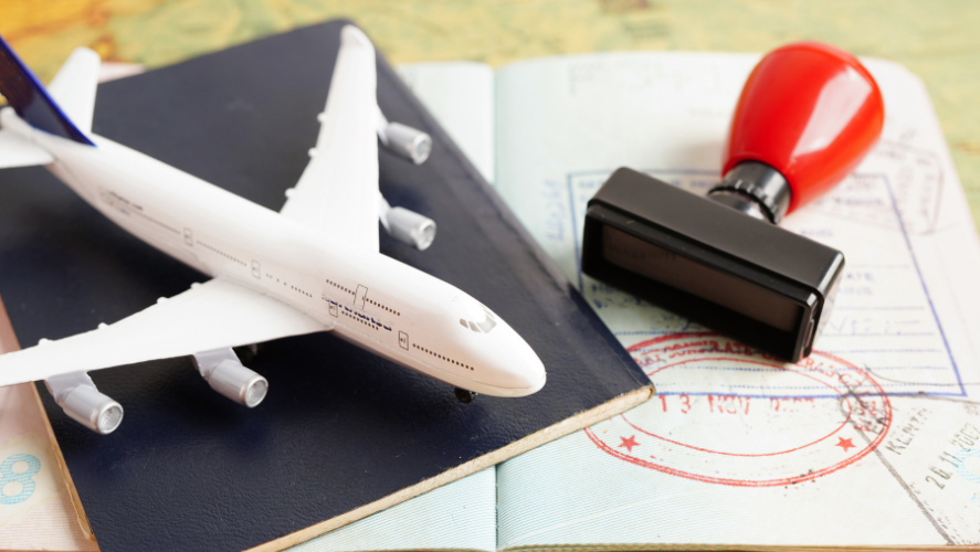 Small model airplane on top of passport on top of immigration papers that are stamped